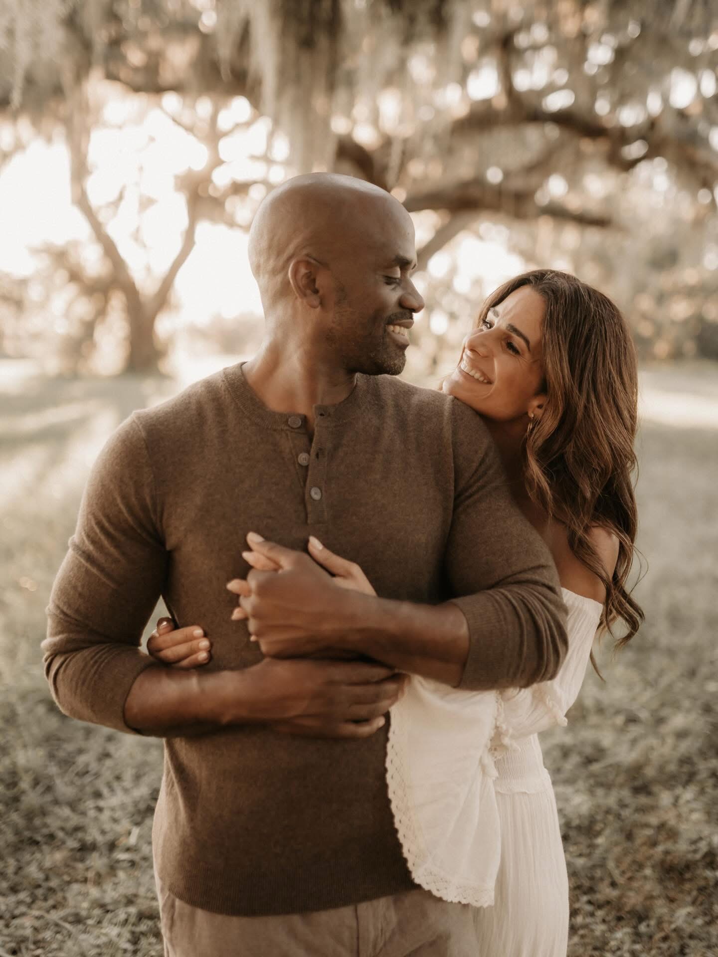 Sherman & Cristina Merricks embracing under oak trees at golden hour
